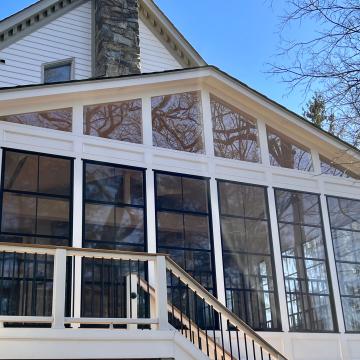 White three season room exterior with tall black-framed windows