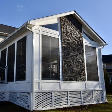 White three season room with screened windows and stone gable
