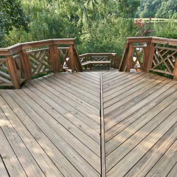 Wood deck with geometric railings overlooking a wooded pond