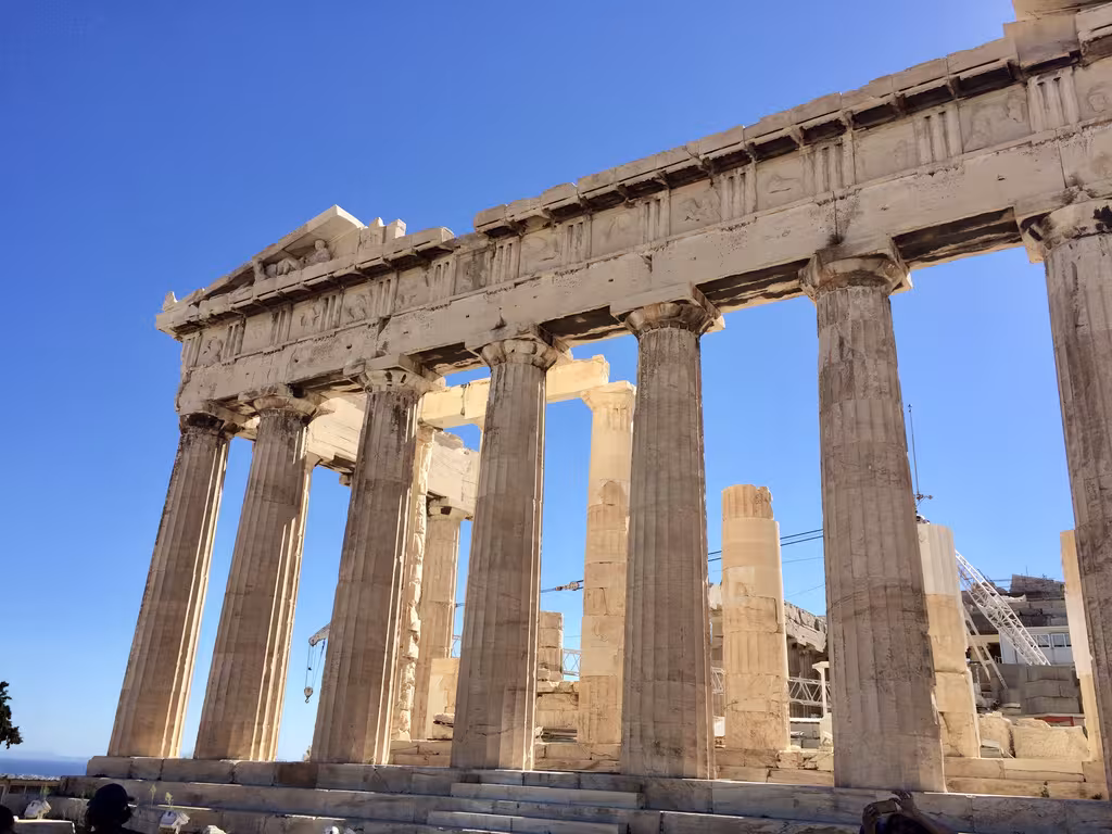 Ancient stone temple columns under a bright blue sky