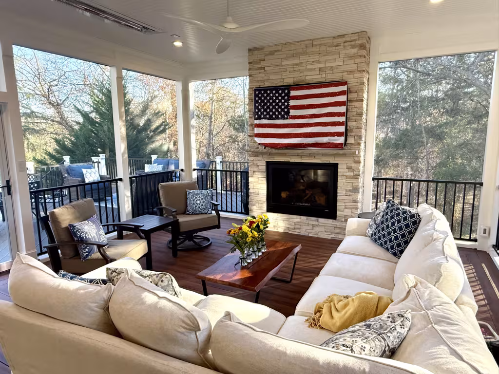 Screen porch seating area with stone fireplace and large windows
